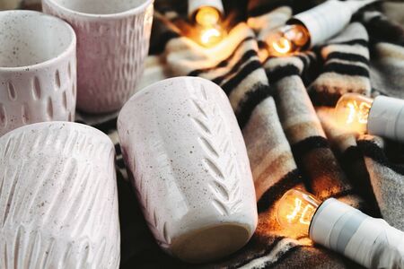 stylish creative ceramics cups and christmas garland lights, holiday celebration conceptの写真素材