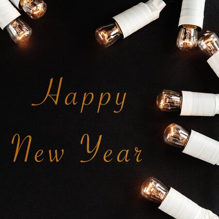 happy new year sign on black background with unusual christmas golden vintage garland lights, simple...