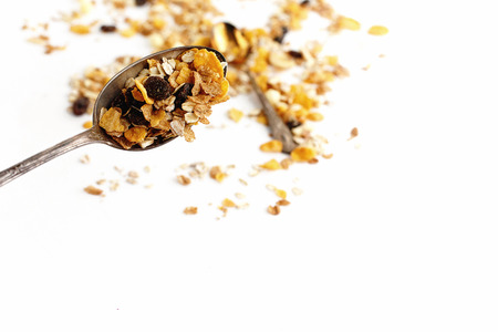 delicious granola muesli cereal with vintage spoon on white background, healthy eating concept