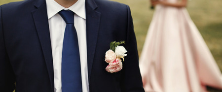 boutonniere on suit, luxury bride and groom posing, stylish wedding couple standing,  romantic moment at botanical garden, space for textの写真素材