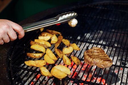 potatos meat garlic and tomato pepper grilling. chef working with tongs. catering in food court at mall concept. space for text. modern kitchenの写真素材