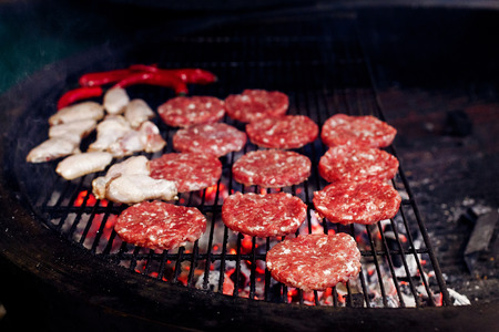 pork meat and chicken grilling for burgers with flames and smoke. catering in food court at mall. space for text. open kitchenの写真素材
