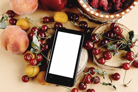 phone with empty screen and delicious fruits on wooden background, rustic summer concept,  space for textの写真素材