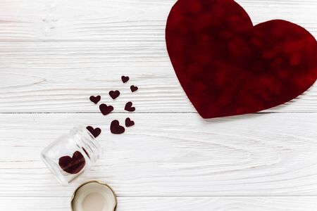 valentine concept. stylish velvet heart and glass jar on white wooden background flat lay. happy valentines day. greeting card with space for text. wedding or birthdayの写真素材