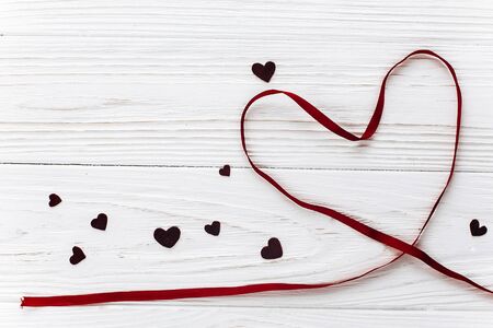 valentine concept. stylish ribbon heart on white wooden background. happy valentines day. greeting card with space for text. wedding or birthday accessoriesの写真素材
