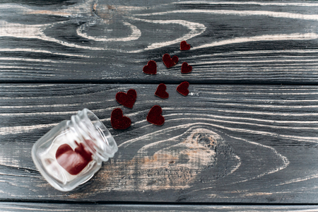 stylish velvet hearts in glass jar  flat lay on black rustic wooden background. happy valentine day. unusual greeting card  with space for text. wedding or birthdayの写真素材