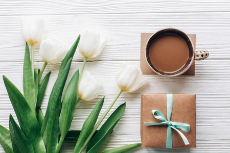 stylish craft present with morning coffee and tulips on white wooden rustic background. flat lay with flowers and gift with space for text. hello spring concept. mothers or womens dayの写真素材