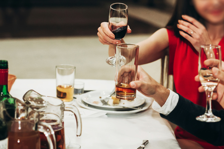 Corporate business man toasting at dinner party table hands close-up, wedding reception guests toast alcohol drinks in glasses for newlyweds, happy people drinking, celebration conceptの写真素材