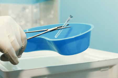 Surgeon doctor taking out sterile needle for syringe with pincers hands close-up, modern hospital equipment for patient treatment, healthcare conceptの写真素材