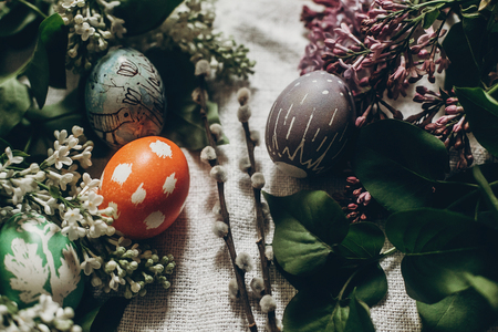 easter eggs with lilac flowers on rustic background and pussy willow. greeting card concept. top view. colorful decorated egg with floral and chicken ornaments. spring holiday. happy easterの写真素材