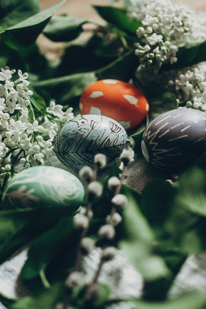 easter eggs with lilac flowers on rustic background and pussy willow. greeting card concept. colorful decorated egg with floral and chicken ornaments. spring holiday. happy easterの写真素材