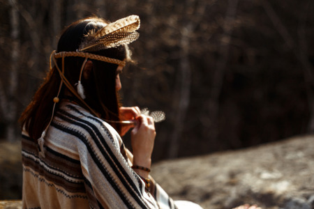 beautiful native indian american woman shaman  sitting on rocks and looking at woods and riverの写真素材
