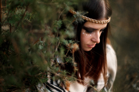beautiful native indian american woman with warrior shaman make up on background of woods