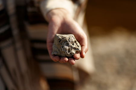 boho woman holding in hand moon shaped textured stone at river beachの写真素材