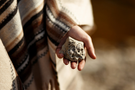 boho woman holding in hand moon shaped textured stone at river beachの写真素材