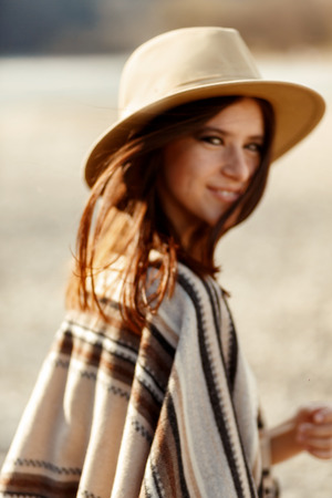 beautiful woman hipster portrait smiling, with romantic look and enjoying, wearing hat and poncho, boho travel conceptの写真素材