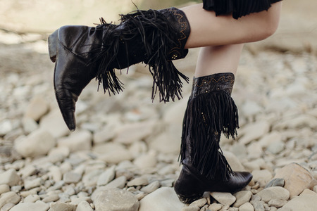 boho girl walking in fringe boot. stylish hipster traveler woman wearing suede boots on river beach. gypsy look. wanderlust summer travel. atmospheric moment. space for text.の写真素材