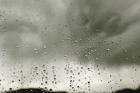 raindrops on window glass on background of gray clouds, rainy weather in mountains, space for textの写真素材