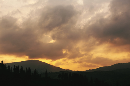 amazing sunset in mountains landscape, sun and clouds and woods in sunlight, tranquil moment of peace concept, space for textの写真素材