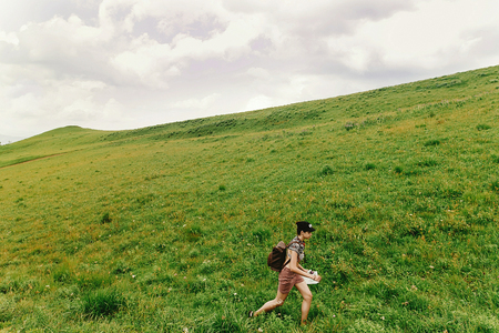 stylish hipster woman traveler walking on hill of summer mountains, travel and adventure  concept, space for textの写真素材