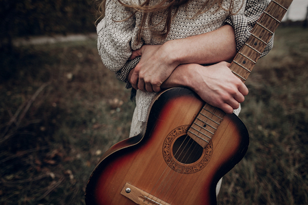 man with guitar hugging his boho gypsy woman in windy field. atmospheric sensual moment. stylish hipster couple in fashionable look. rustic wedding conceptの写真素材