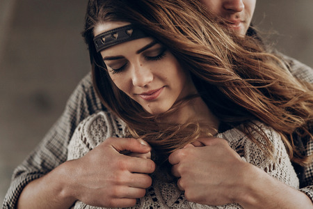 stylish hipster couple gently hugging. man in hat  embracing boho woman in knitted sweater. atmospheric sensual moment. rustic fashionable look.の写真素材