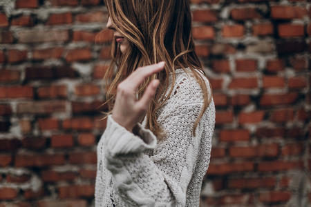 stylish hipster gypsy woman posing in knitted sweater on background of brick wall, holding hair. atmospheric sensual moment. boho country fashionable look. free peopleの写真素材