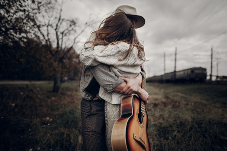 stylish hipster couple dancing in windy field. boho gypsy woman and man in hat embracing in windy field. atmospheric motion moment. fashionable look. rustic wedding conceptの写真素材