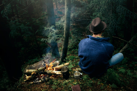 stylish hipster traveler camping in sunny forest in the mountainsの写真素材