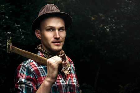 stylish hipster lumberjack with ax in the sunny forest in mountains
