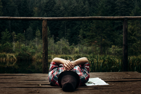 stylish hipster traveler playing harmonica at sunny lake in the forest in mountainsの写真素材