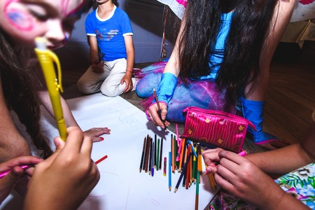 group of  kids drawing with colorful pencils and having fun at birthday celebration in restaurantの写真素材