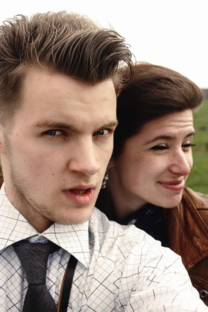stylish brunette beautiful woman and man in love having funny selfies in windy spring fieldの写真素材