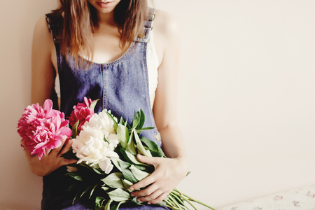 woman hipster in denim dress holding peony bouquet in the morning, sweet romantic moment , space for textの写真素材