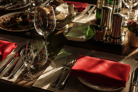 luxury glasses and plates with napkins on stylish decorated table with food at wedding reception. expensive catering at restaurant for celebrations. transparent glass and silver cutleryの写真素材