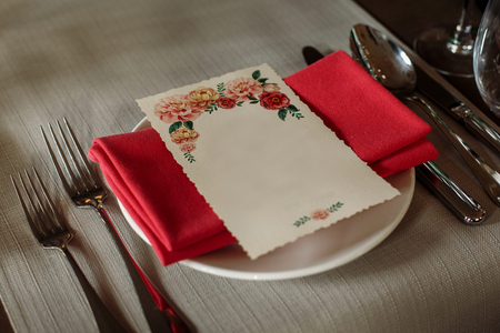 Elegant wedding reception catering, luxury table arrangement - floral greeting card on red napkin near expensive silverware close-up, fine dining conceptの写真素材