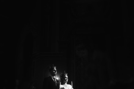 wedding ceremony at church. stylish groom and bride holding candles and giving vows. spiritual ...