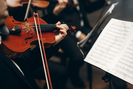 Elegant string quartet performing at wedding reception in restaurant, handsome man in suits playing violin and cello at theatre play orchestra close-up, music conceptの写真素材