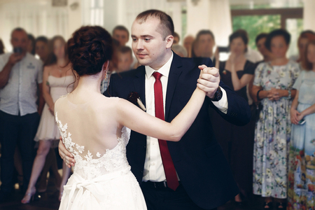 Happy newlywed couple holding hands and dancing at evening wedding reception in luxury dance hall, romance first dance conceptの写真素材