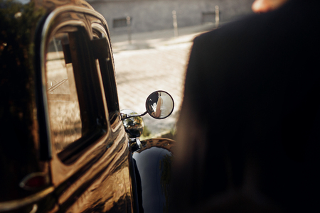 unusual view on luxury elegant wedding couple hugging, reflection in mirror of hands at stylish black car. retro style. romantic momentの写真素材