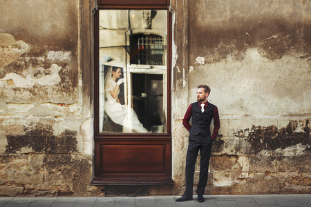 elegant gorgeous bride  drinking coffee in window and stylish groom posing at building in street outdoors cafe. unusual luxury wedding couple in retro style. romantic momentの写真素材