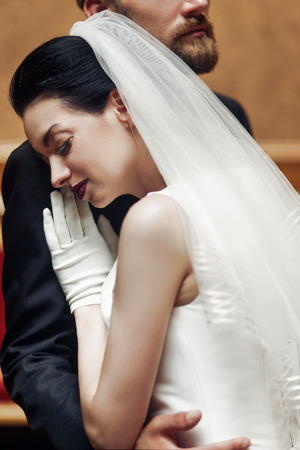 elegant gorgeous bride gently hugging stylish groom in amazing rich room. unusual wedding couple in retro style. romantic momentの写真素材