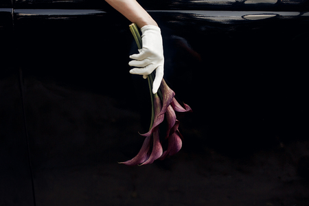 elegant gorgeous bride hand in silk glove holding wedding bouquet of callas  on backgound of stylish luxury black car. unusual adorning in retro style. minimalisticの写真素材