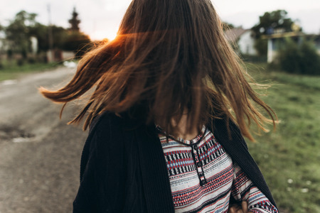 happy woman waving hair in sunlight summer sunset. moment of carefree and true happiness. girl having fun and dancing in countryside in warm sunshineの写真素材