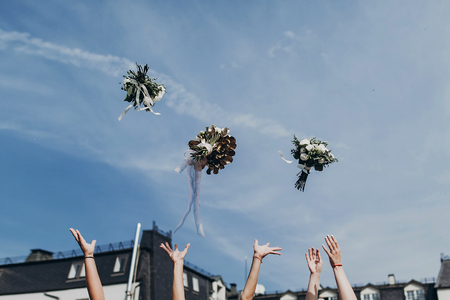 luxury bride and bridesmaids throwing up bouquets in sky, sunny wedding reception.  space for text. joyful moment. bride with girls having fun in wedding morningの写真素材