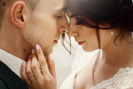 gorgeous bride and stylish groom gently hugging in sunny light. sensual tender emotional moment of luxury wedding couple embracing. portraitsの写真素材