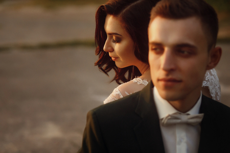 gorgeous bride and stylish groom posing in the evening warm sunlight. sensual romantic moment of luxury wedding couple in amazing sunsetの写真素材