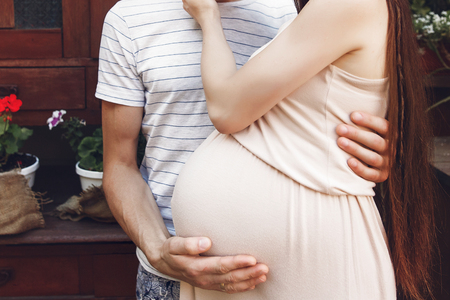 pregnant woman with big belly bump hugging with her husband. happy family waiting for baby. tender moments of parenthood. pregnancy conceptの写真素材