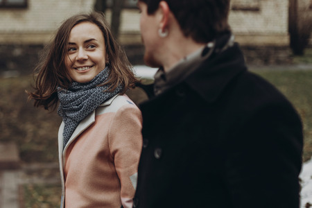 romantic stylish couple walking and laughing in autumn park. man and woman having fun and talking. family togetherness concept.  atmospheric moment.の写真素材