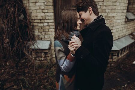 romantic stylish couple hugging gently and smiling in autumn park. man and woman embracing, showing true feelings. family togetherness conceptの写真素材